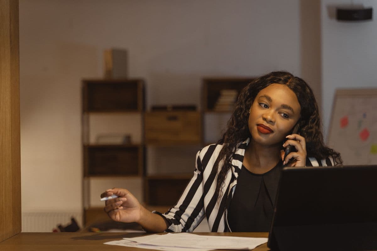 Agent au téléphone dans un bureau, illustrant le poste d'Agent Executive Admin — collecte de prêts, administration et Shopify.